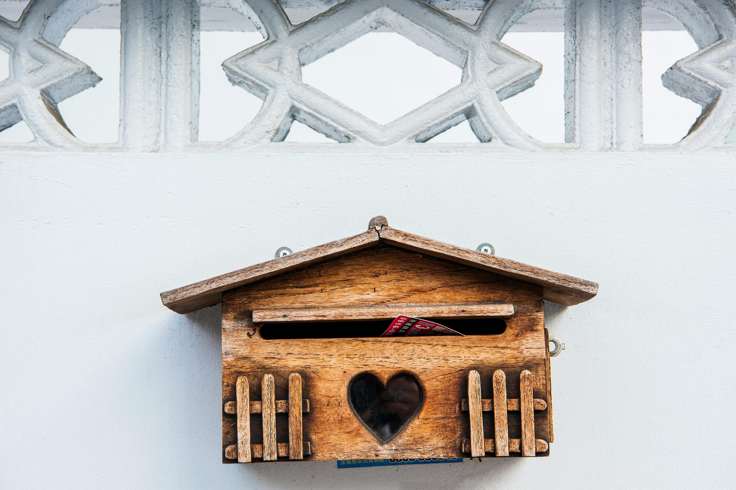 A charming wooden mailbox with heart design on a white exterior wall in Taichung, Taiwan.