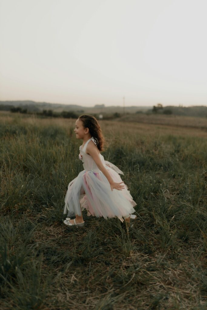 A young child joyfully running in a grassy field at sunset, capturing freedom and play.