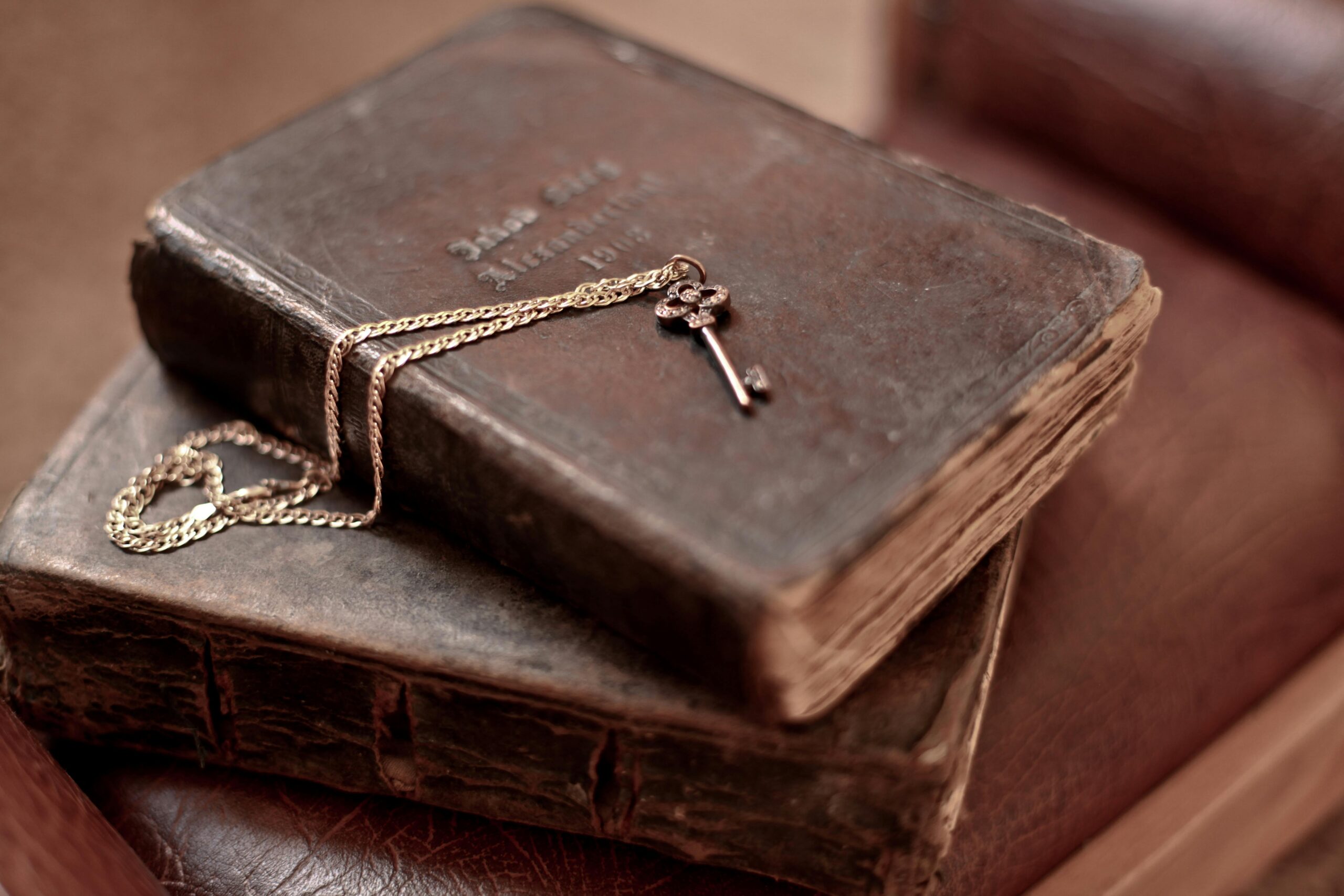 A detailed close-up of a vintage key resting on rustic antique books, evoking nostalgia.